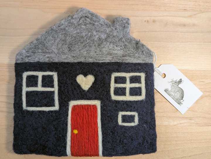 A felted navy blue house with a heather grey roof and a red yellow door with a heart motif above it.