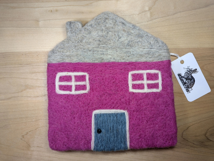 A felted pink house with a light grey roof and a country blue door.