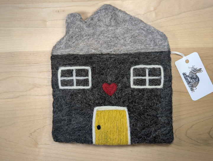 A felted dark grey house with a heather grey roof and a yellow door with a heart motif above it.