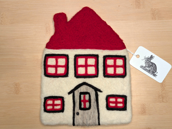 A felted white house with a red roof, black and red trim around the windows, and a grey door.