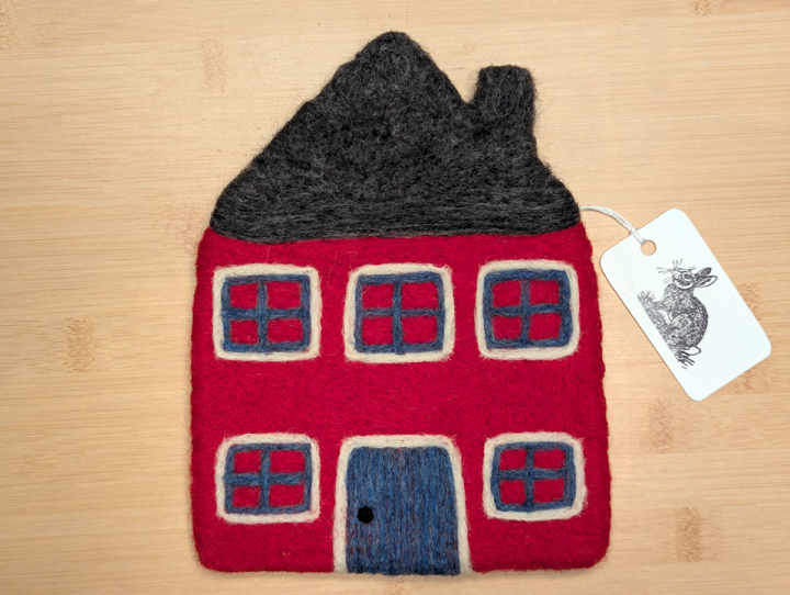 A felted red house with a dark grey roof, blue and white trim around the windows, and a blue door.