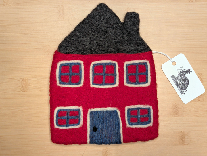 A felted red house with a dark grey roof, blue and white trim around the windows, and a blue door.