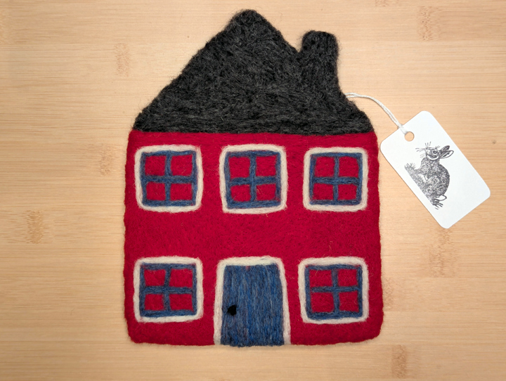 A felted red house with a dark grey roof, blue and white trim around the windows, and a blue door.