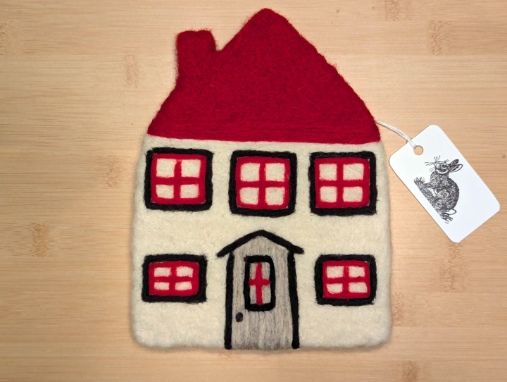 A felted white house with a red roof, black and red trim around the windows, and a grey door.