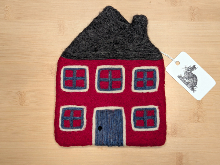 A felted red house with a dark grey roof, blue and white trim around the windows, and a blue door.