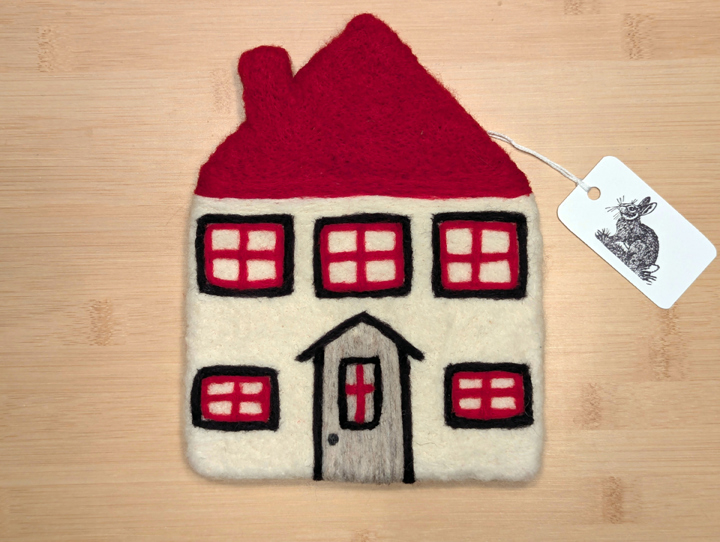 A felted white house with a red roof, black and red trim around the windows, and a grey door.